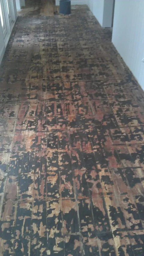 Badly worn floor before work, the old finish black and flaking away in patches across the boards