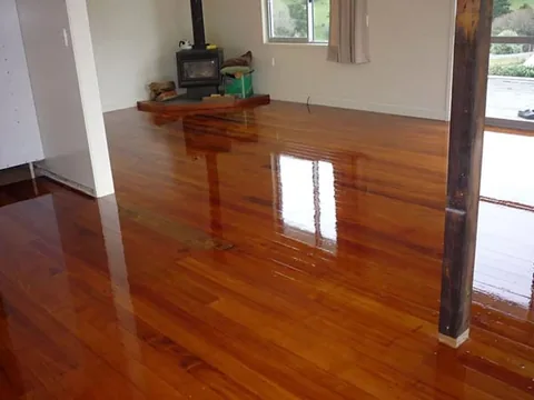 High gloss timber floor in a living room with a wood burner, opening onto a deck