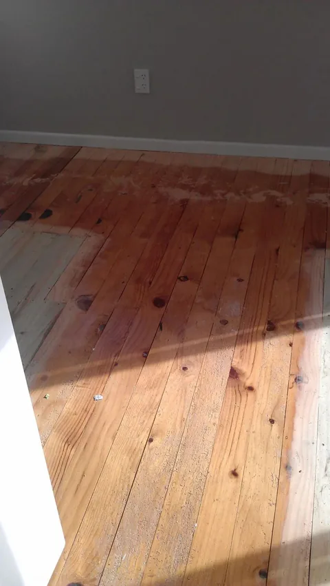 Floor half sanded, the cleaned pale timber meeting the old darkened finish in a straight line
