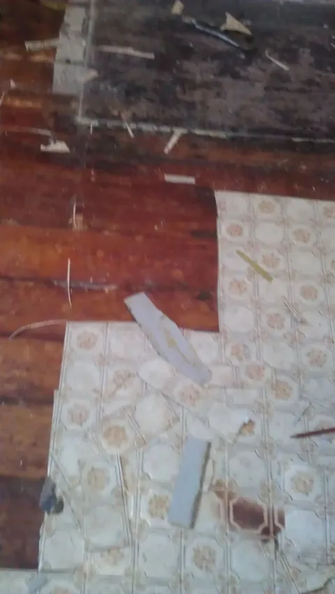 Old floor with patterned lino and paper backing still stuck to the boards, before stripping