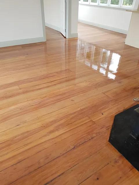 The same repaired floor after sanding and coating, the filled gaps now level and the boards evenly glossy
