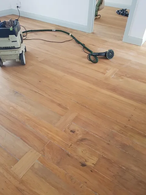 Repaired and resanded floor with replacement boards let in, sanding machine and lead still on the floor