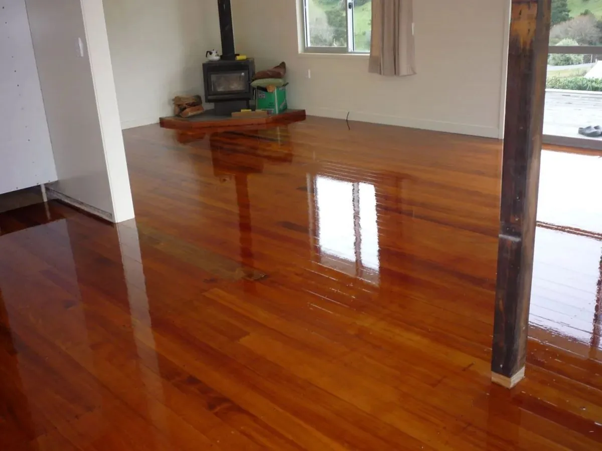 Rich red-brown timber floor with a high gloss finish in a living room with a wood burner and a timber post
